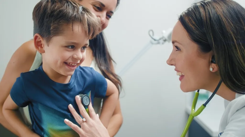 NeuMed provider examining a smiling child with a stethoscope