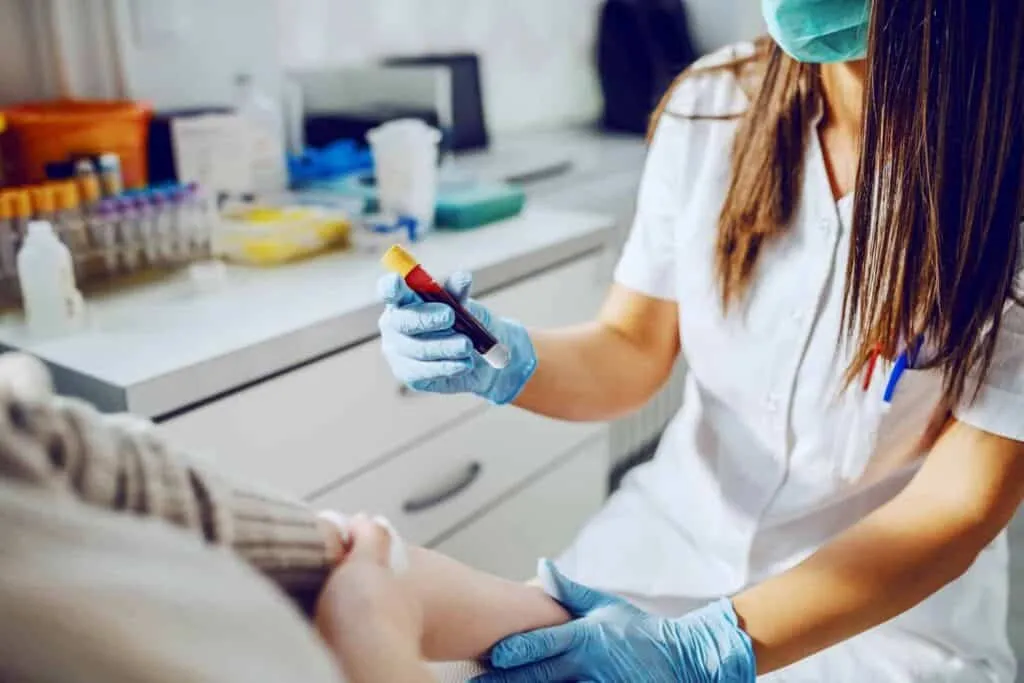 Clinician in gloves holding a blood sample vial after a lab draw