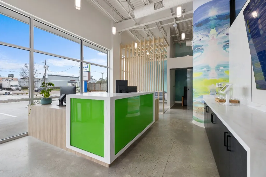 NeuMed clinic lobby with a lime-green reception desk and infusion therapy menu