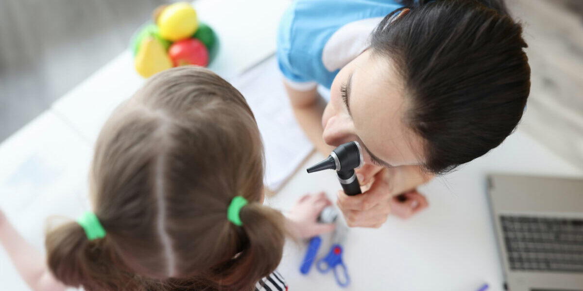 Otolaryngologist looks at little girl ear with otoscope. Hearing test in children concept