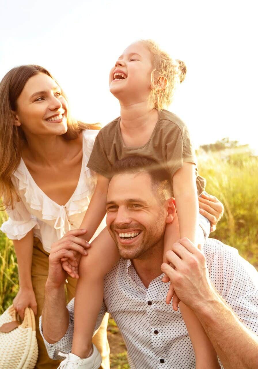 Father carrying daughter on shoulders with wife Family enjoying the outdoors without suffering from allergies