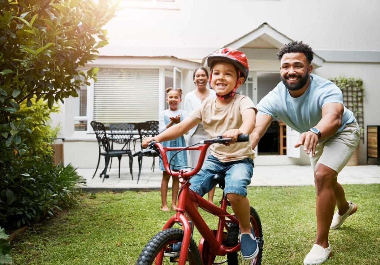 Father helping son ride bike outside
