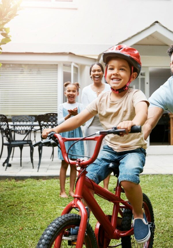 Father helping son ride bike outside