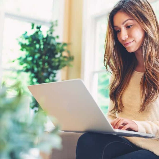 Happy young latina woman working on her laptop at home